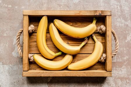 top view of ripe bananas in wooden box on weathered surfaceの写真素材