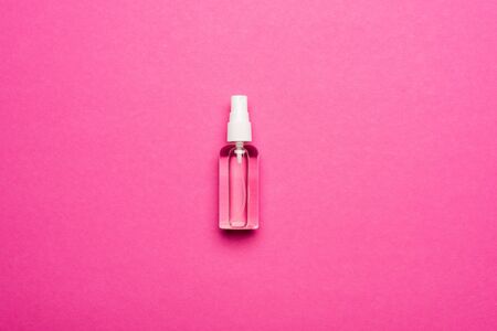 top view of transparent spray bottle with liquid hand sanitizer on pinkの写真素材