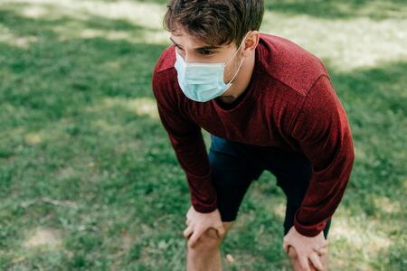 Young sportsman in medical mask standing in parkの写真素材
