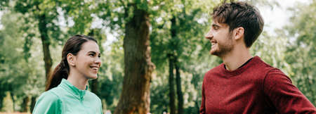 Panoramic crop of smiling sportswoman looking at boyfriend in parkの写真素材