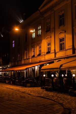 dark street and silhouette of people sitting in cafe with terrace