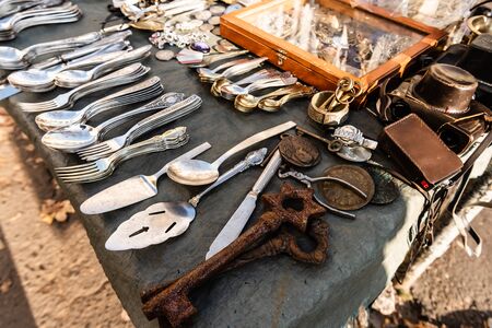 stall on flea market with vintage cutlery, rusty keys, camera and souvenirs in lviv, ukraine