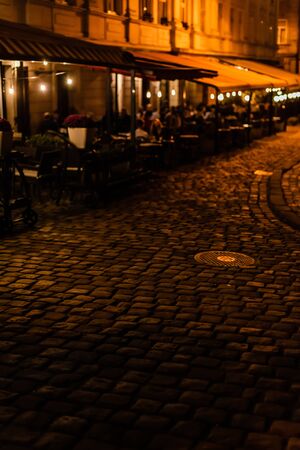 selective focus of paving stones on road near cafe with terraceの写真素材