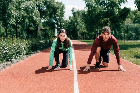 Couple standing in starting position on running track in parkの写真素材