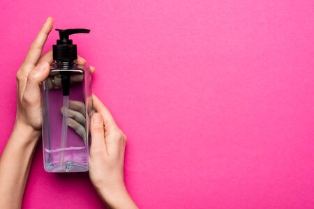 cropped view of woman holding bottle with hand sanitizer on pinkの写真素材
