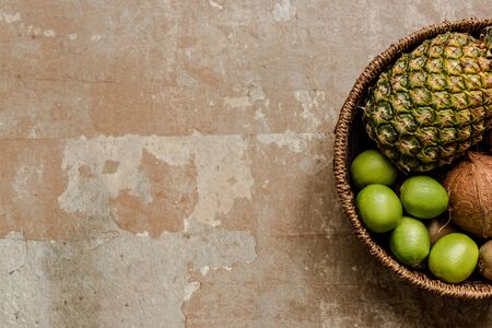 top view of ripe exotic fruits in wicker basket on weathered surface