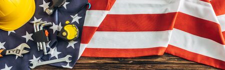 panoramic crop of instruments and safety helmet on american flag, labor day conceptの写真素材