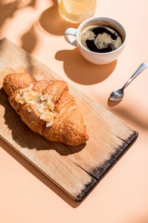 fresh croissants on wooden board and cup of coffee for breakfast on beige tableの写真素材