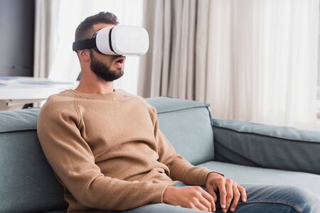 surprised man in virtual reality headset in living room