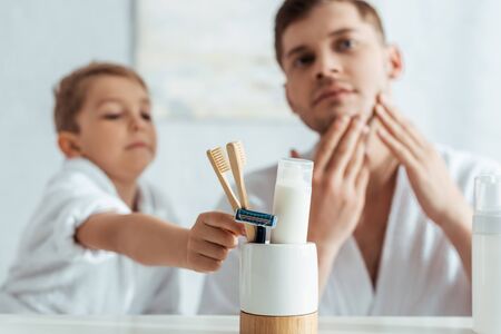 selective focus of man touching face while adorable son taking toothbrushの写真素材