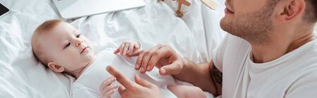 cropped view of young father touching hands of adorable infant, horizontal imageの写真素材