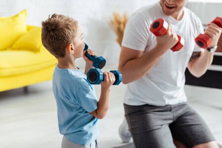 cropped view of man near son exercising with dumbbells at homeの写真素材