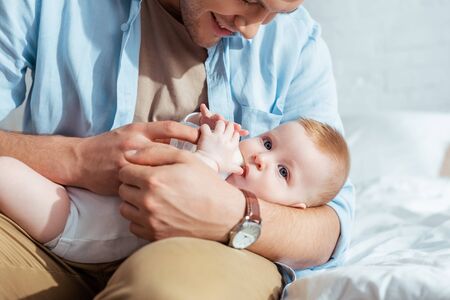 cropped view of smiling father feeding adorable son with milk from baby bottleの写真素材