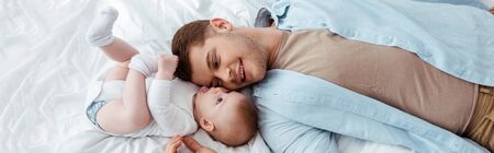 top view of happy father lying face to face with cute baby boy, horizontal image