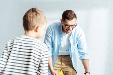 back view of boy and smiling father playing table football at homeの写真素材