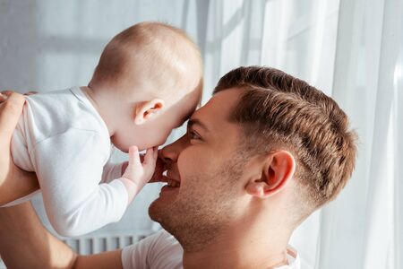 happy father holding adorable boy baby face to faceの写真素材
