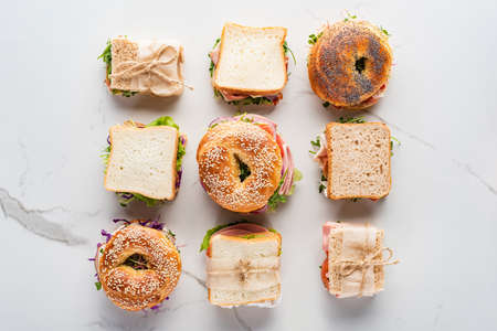 flat lay with fresh sandwiches and bagels on marble white surfaceの写真素材