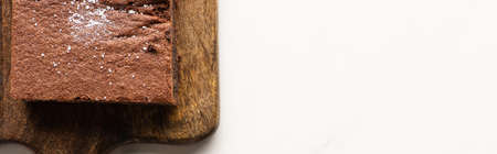 top view of delicious brownie piece on wooden cutting board on white background, panoramic shotの写真素材