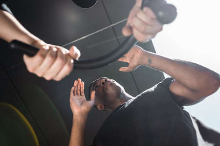 bottom view of police officer holding truncheon near tattooed african american man, racism conceptの写真素材