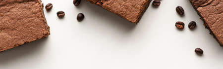 top view of delicious brownie pieces with coffee beans on white background, panoramic shot