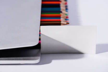 selective focus of empty business card and colored pencils in modern laptop on white background
