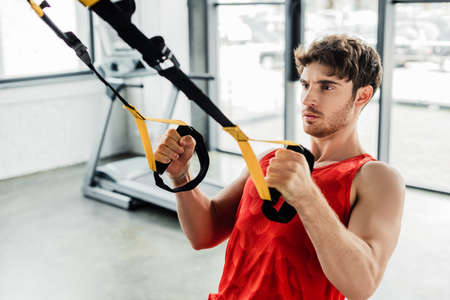 handsome sportsman exercising with elastics in gymの写真素材