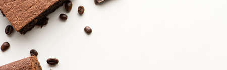 top view of delicious brownie pieces with coffee beans on white background, panoramic shot