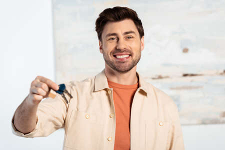 Selective focus of smiling man looking at camera while holding keys of new houseの写真素材