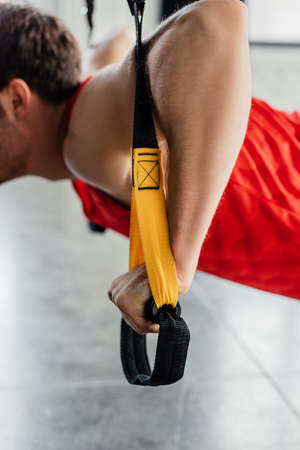 cropped view of strong man working out with elastics in gymの写真素材