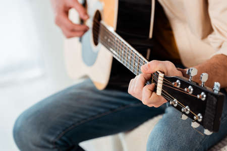 Cropped view of man playing acoustic guitar