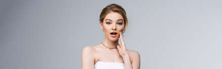 panoramic shot of shocked bride looking at camera isolated on grey