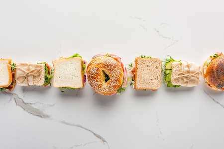 flat lay with fresh sandwiches and bagel on marble white surfaceの写真素材