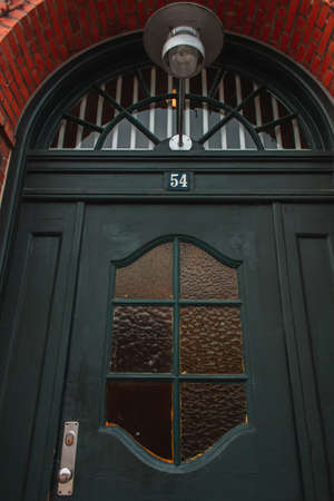 Low angle view of lantern above black door on brick facade of house, Copenhagen, Denmarkの写真素材