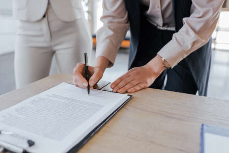 cropped view of businesswoman signing contract near coworkerの写真素材