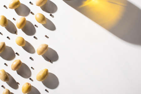 shadow of olive oil near green olives and black pepper on white background