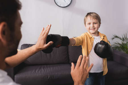 selective focus of smiling boy in boxing gloves fighting with fatherの写真素材