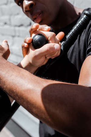 cropped view of police officer holding police baton near african american man on street, racism conceptの写真素材