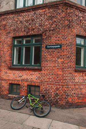 Bicycle on walkway near brick facade of building in Copenhagen, Denmark
