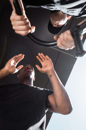 bottom view of policeman holding truncheon near tattooed african american man, racism concept