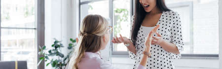 panoramic crop of emotional businesswomen quarreling in officeの写真素材