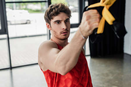 selective focus of sportive man working out with elastics in gym