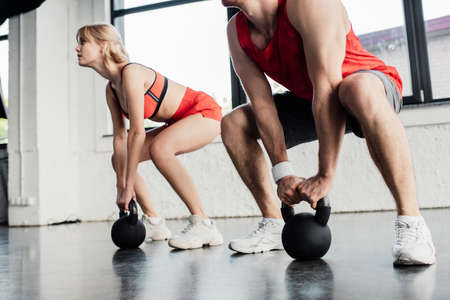 selective focus of sport couple exercising with heavy dumbbells in gymの写真素材