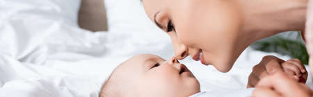 horizontal image of beautiful mother looking at infant son lying on bed