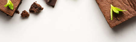 top view of delicious brownie pieces with mint on white background, panoramic shot
