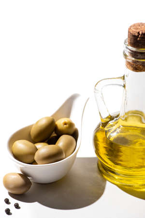 olive oil in jar near green olives and black pepper on white backgroundの写真素材