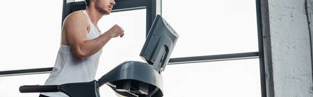 panoramic crop of man in sportswear running on treadmill