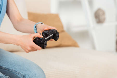 Cropped view of woman holding joystick while playing video game at home
