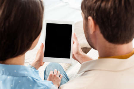 Back view of young couple holding digital tablet with blank screenの写真素材