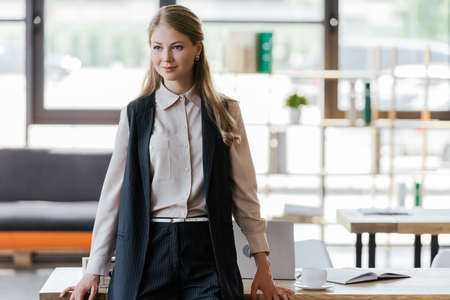 beautiful businesswoman standing near table in modern officeの写真素材