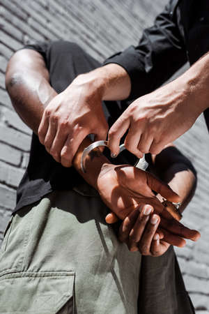 low angle view of policeman touching handcuffed african american manの写真素材